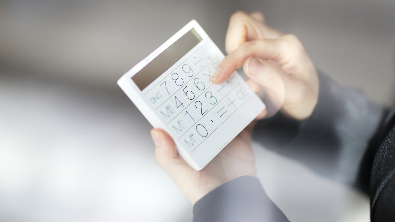 A woman is operating a calculator; image used for HSBC Credit Card Fees and Charges.