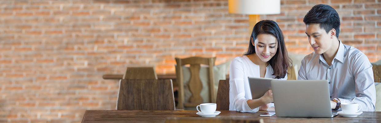 A young lady is having tea and browsing on her tablet together with a young man.